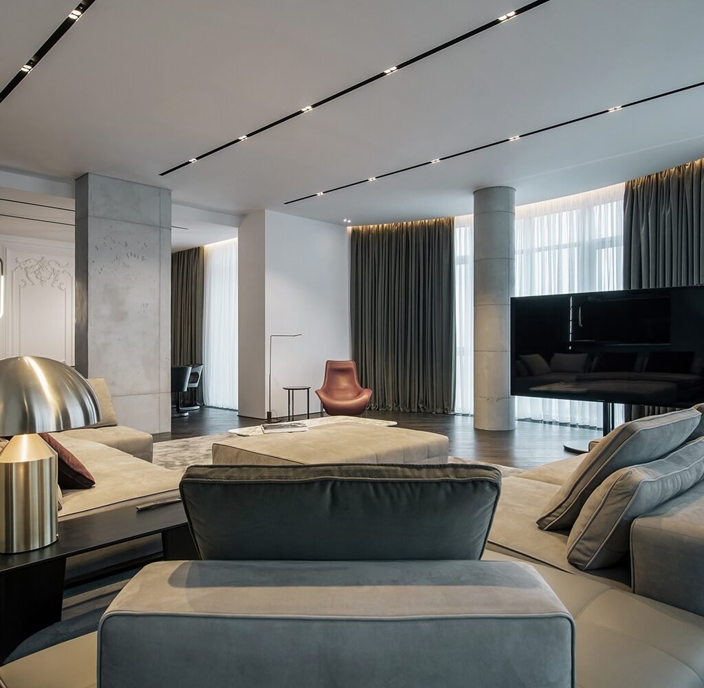 Apartment living room interior design in Dubai with contemporary sectional seating, modern TV and floor-to-ceiling curtains