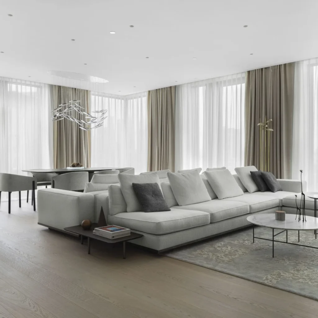 Apartment renovation in Dubai with open living and dining room, neutral sectional sofa and floor-to-ceiling windows