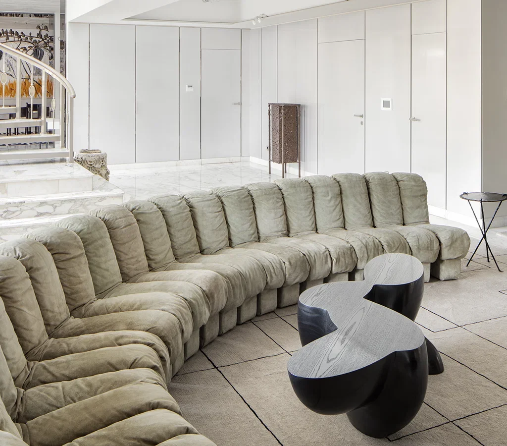 Apartment renovation in Dubai living room with curved sectional sofa, marble flooring and sculptural coffee tables