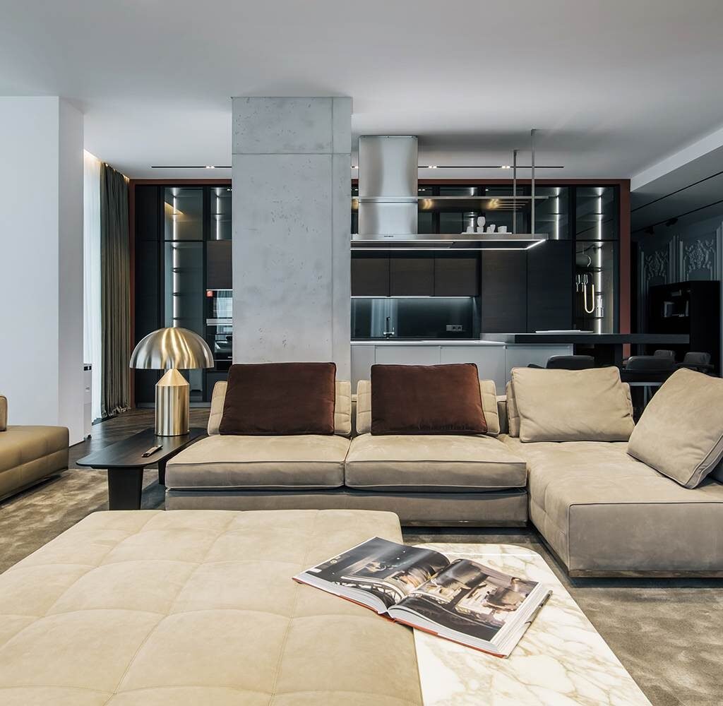 Apartment interior design in Dubai with an open dark kitchen, contemporary sofa and integrated living space