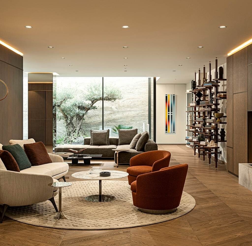 Bespoke apartment interior design in Dubai featuring orange lounge chairs, custom shelving and warm wood flooring