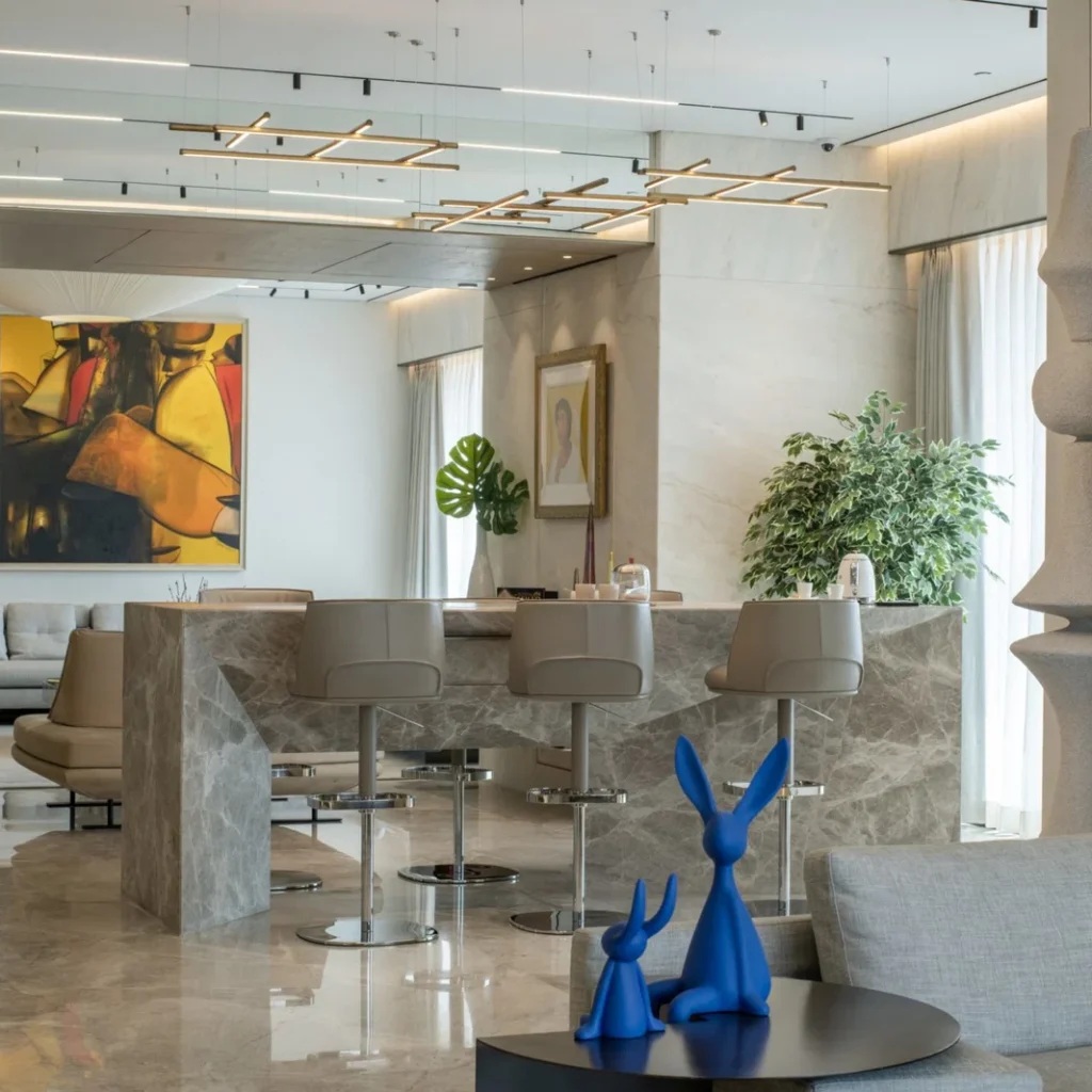 Apartment dining area interior design in Dubai featuring a marble bar, contemporary seating and statement artwork
