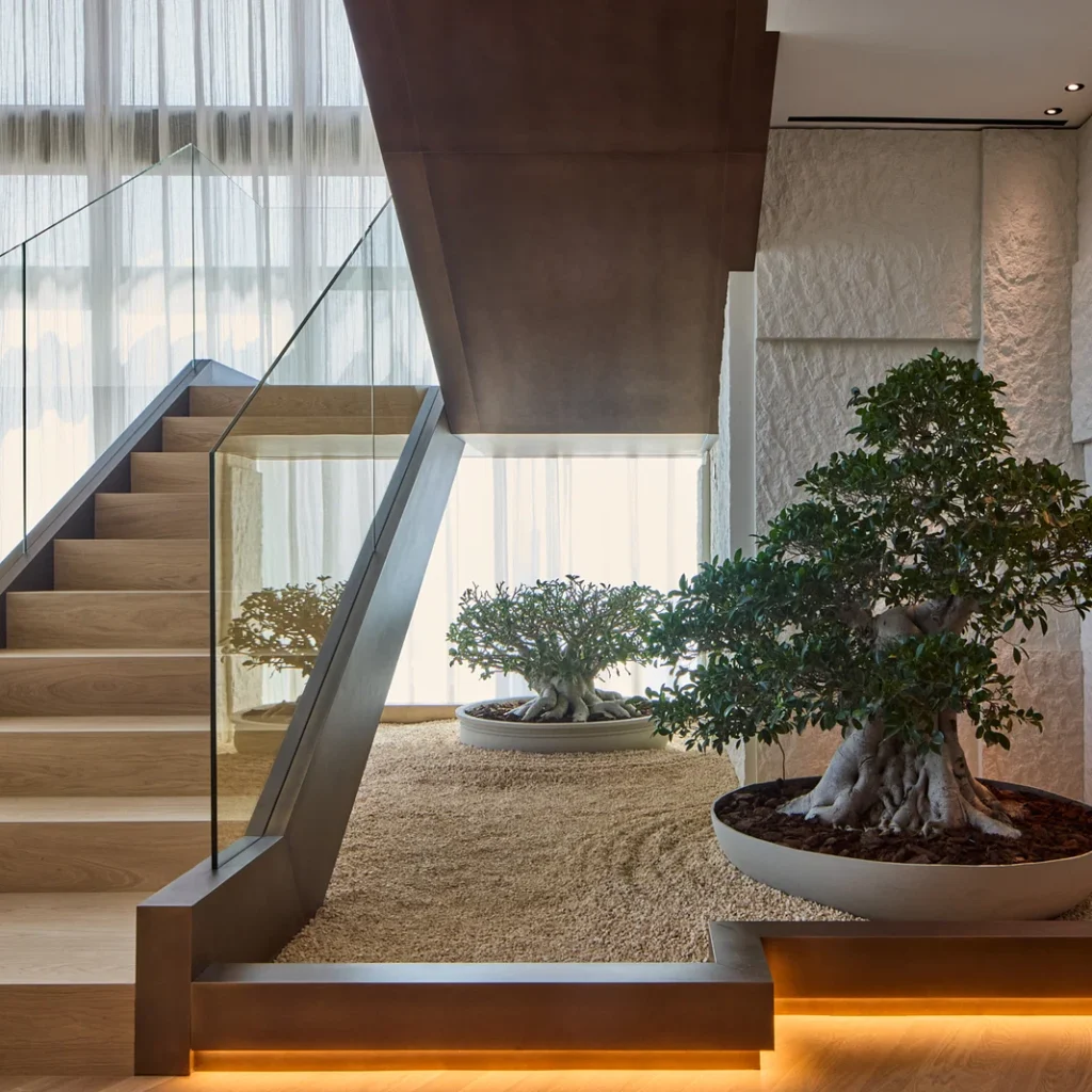 Penthouse interior design in Dubai featuring a modern staircase, glass balustrade and integrated indoor landscaping