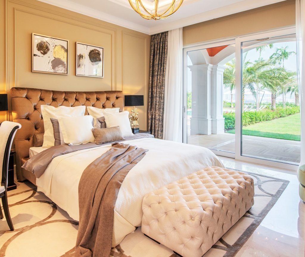 Villa bedroom interior fit out in Dubai featuring a tufted headboard, decorative wall panels and garden views