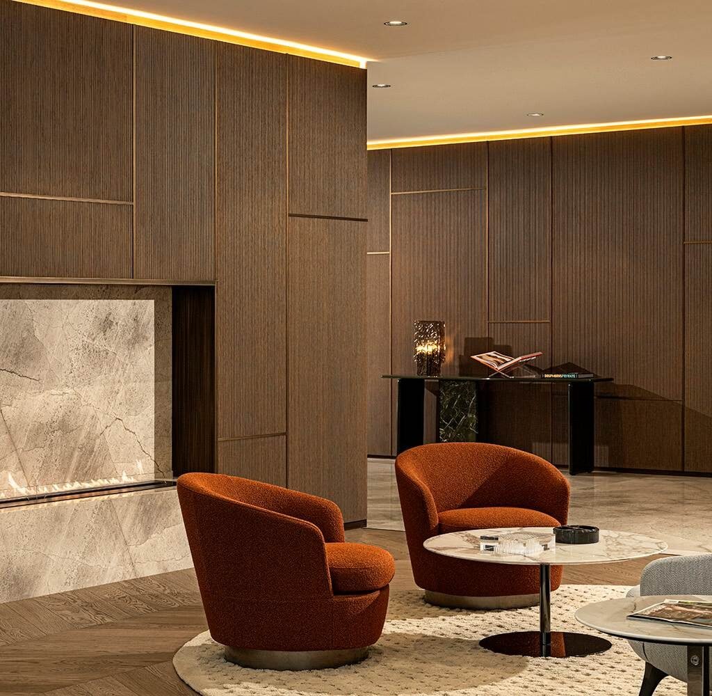 High-end apartment interior design in Dubai with sculptural orange armchairs, stone fireplace and wood wall panels