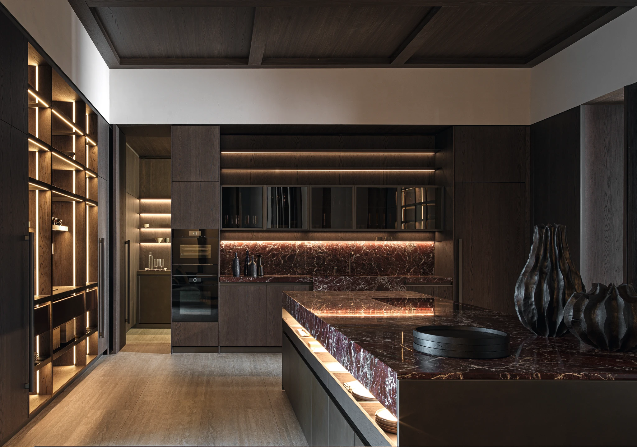 Dark wood kitchen with a burgundy veined island, matching splashback, built-in ovens and illuminated shelving.