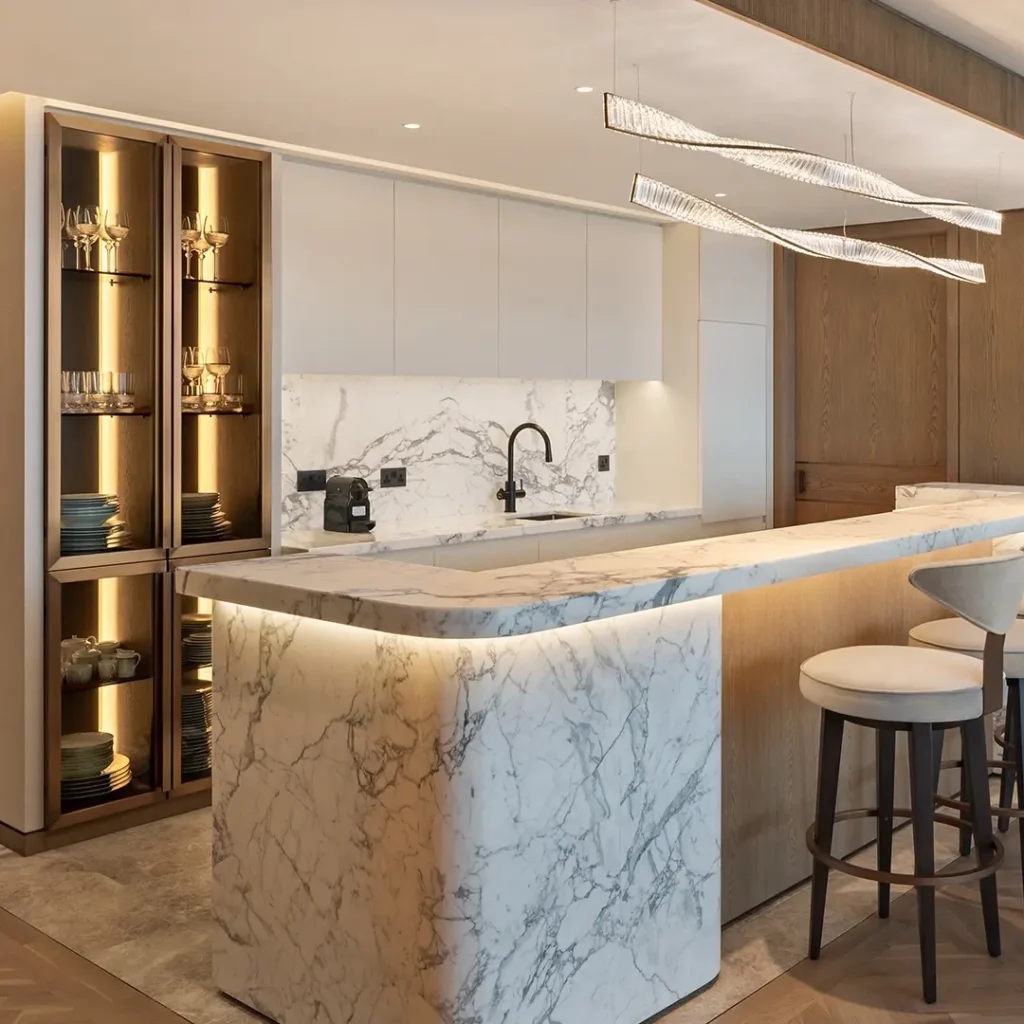 Penthouse renovation in Dubai featuring a marble kitchen island, custom cabinetry, display storage and contemporary lighting